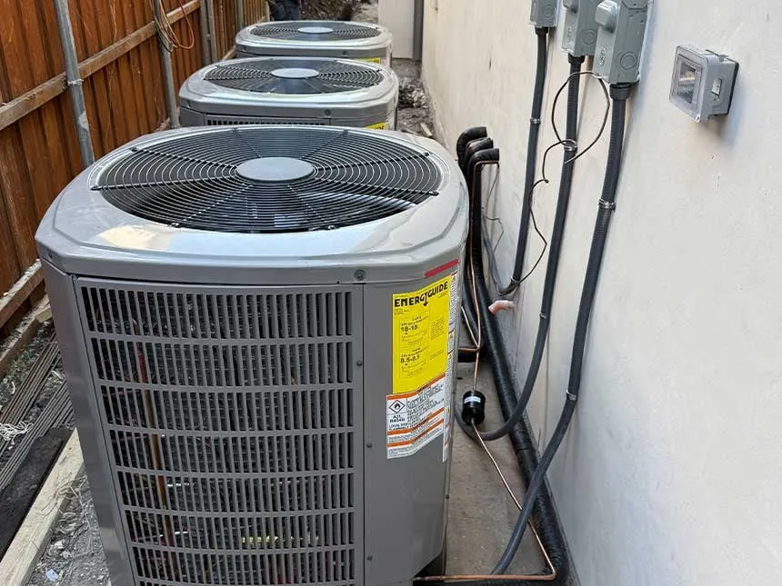 Three outdoor air conditioning condenser units lined up along the side of a home with EnergyGuide labels visible — Cold Factor AC repair service in Flower Mound, TX