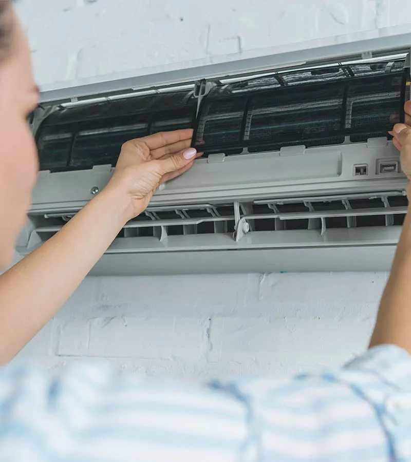 Homeowner removing and cleaning a dirty filter from a wall-mounted mini split air handler