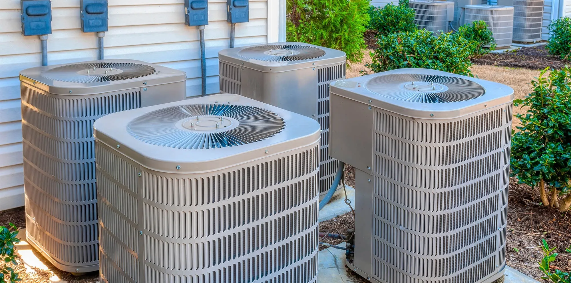 Multiple outdoor AC condenser units at a residential property with technician equipment on site -- Cold Factor HVAC Flower Mound TX
