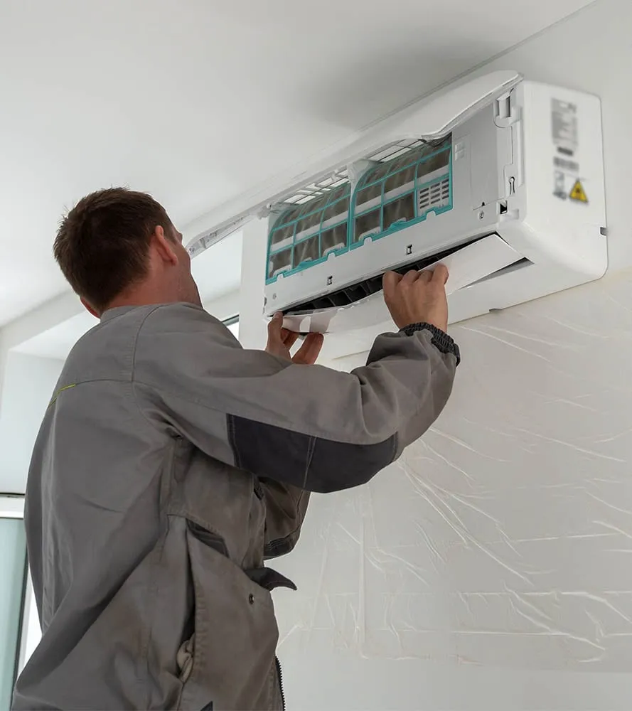 Technician installing a ductless mini split indoor air handler on a wall -- Cold Factor mini split installation services