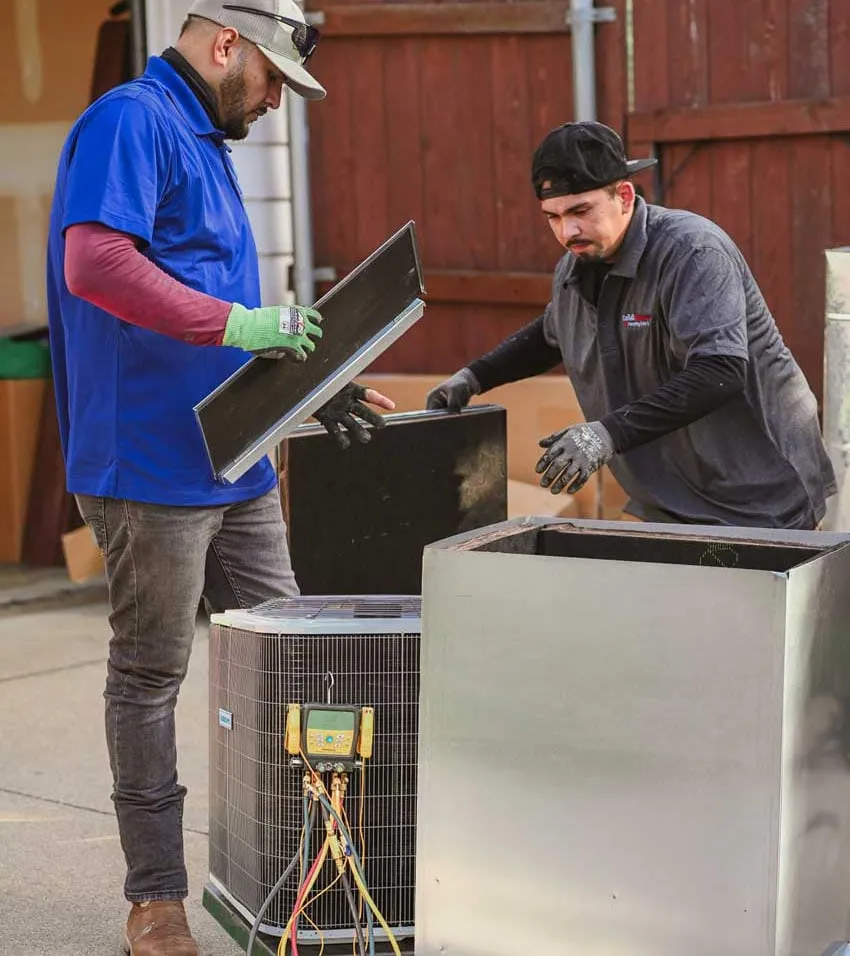 old Factor technicians removing an AC condenser panel with refrigerant diagnostic gauges during AC repair in Lewisville TX