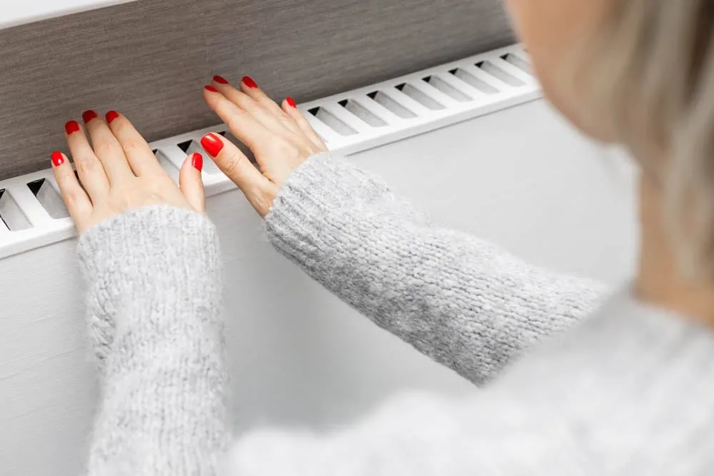 Hand hovering over heating vents